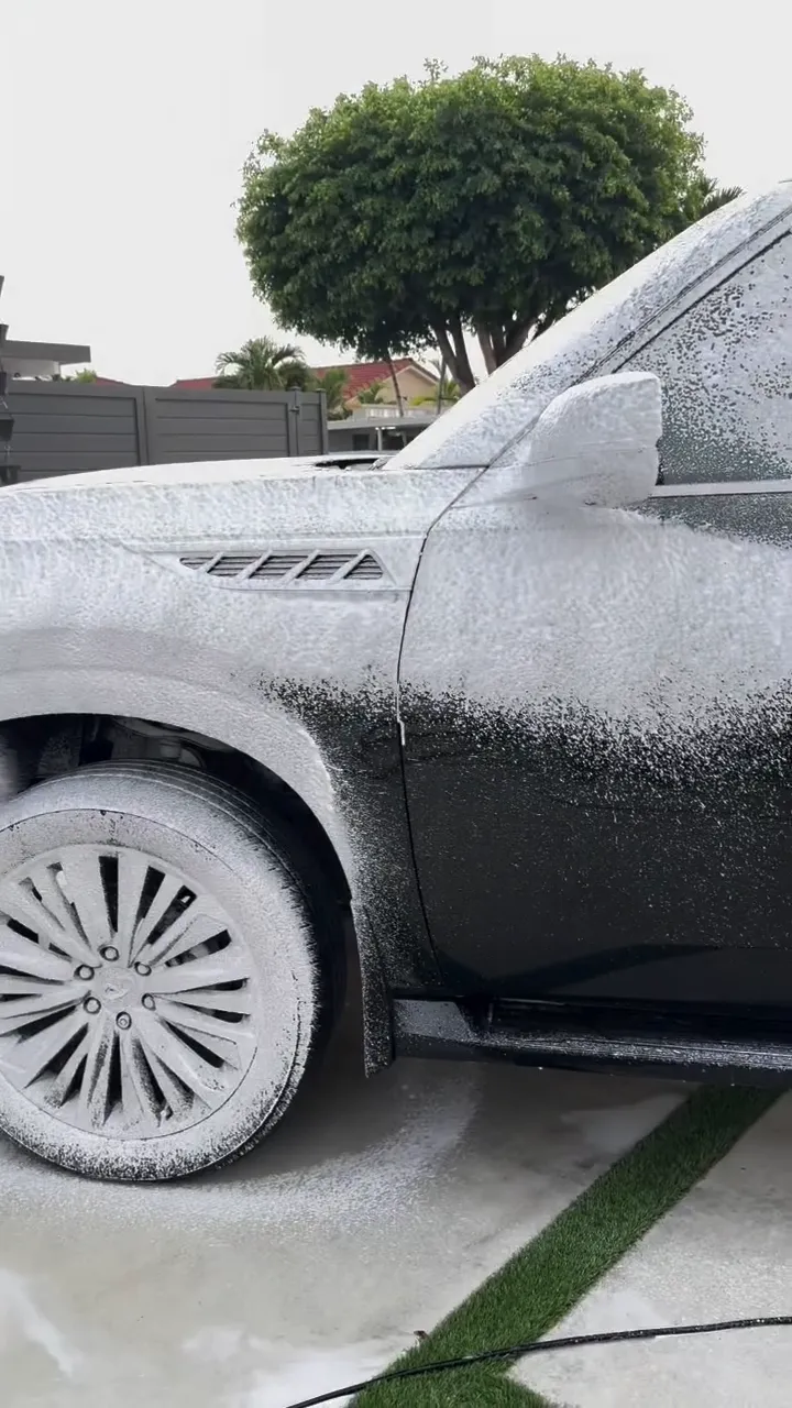 Black Infiniti SUV covered in foam during a wash